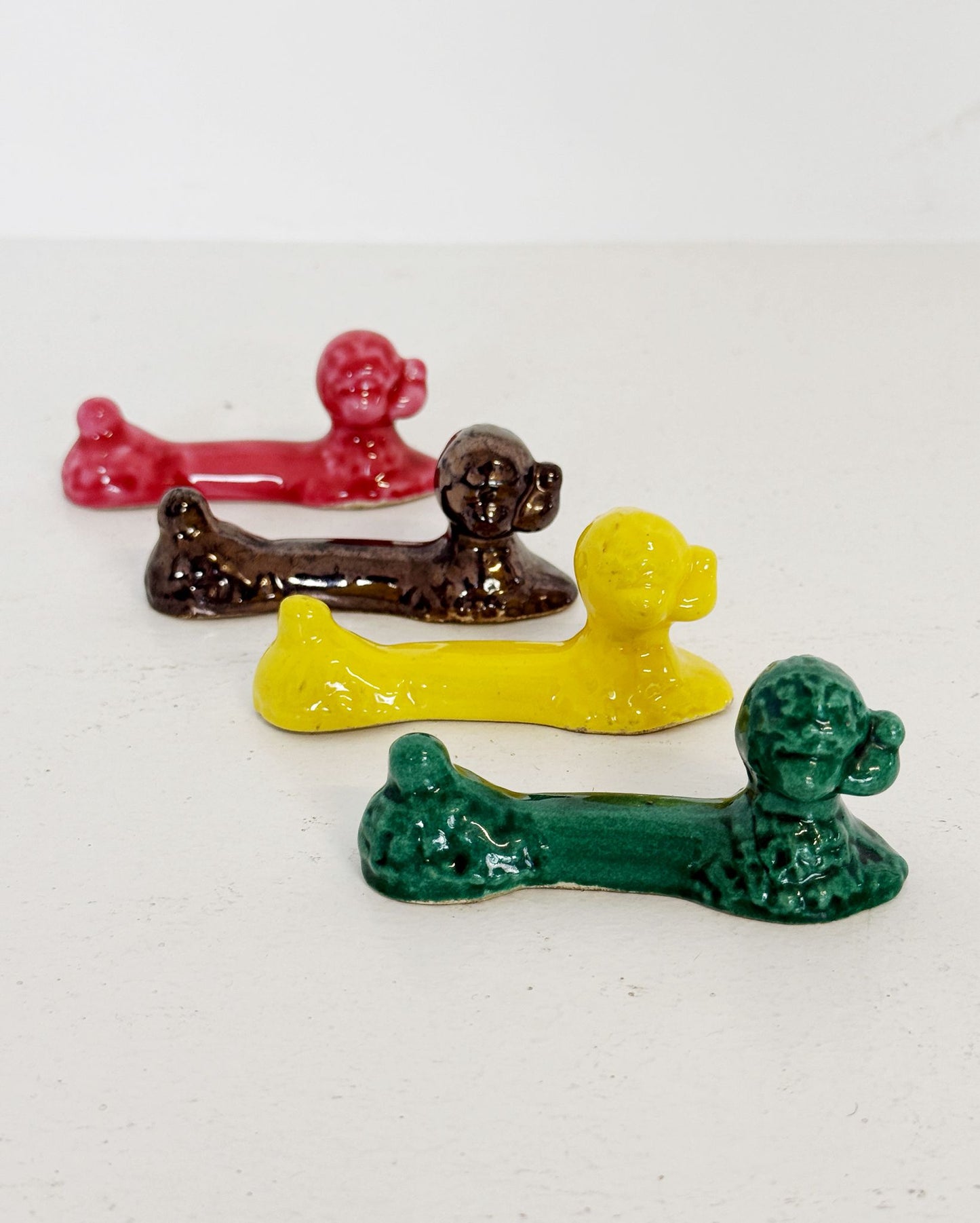 Set of four glazed ceramic cutlery rests in the shape of a reclining poodle