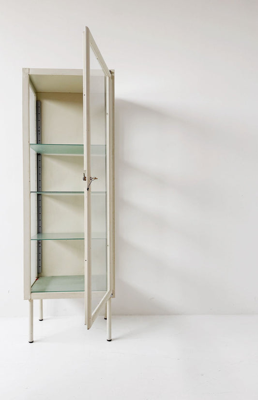 This ivory-colored lacquered metal display cabinet features a simple, functional design
