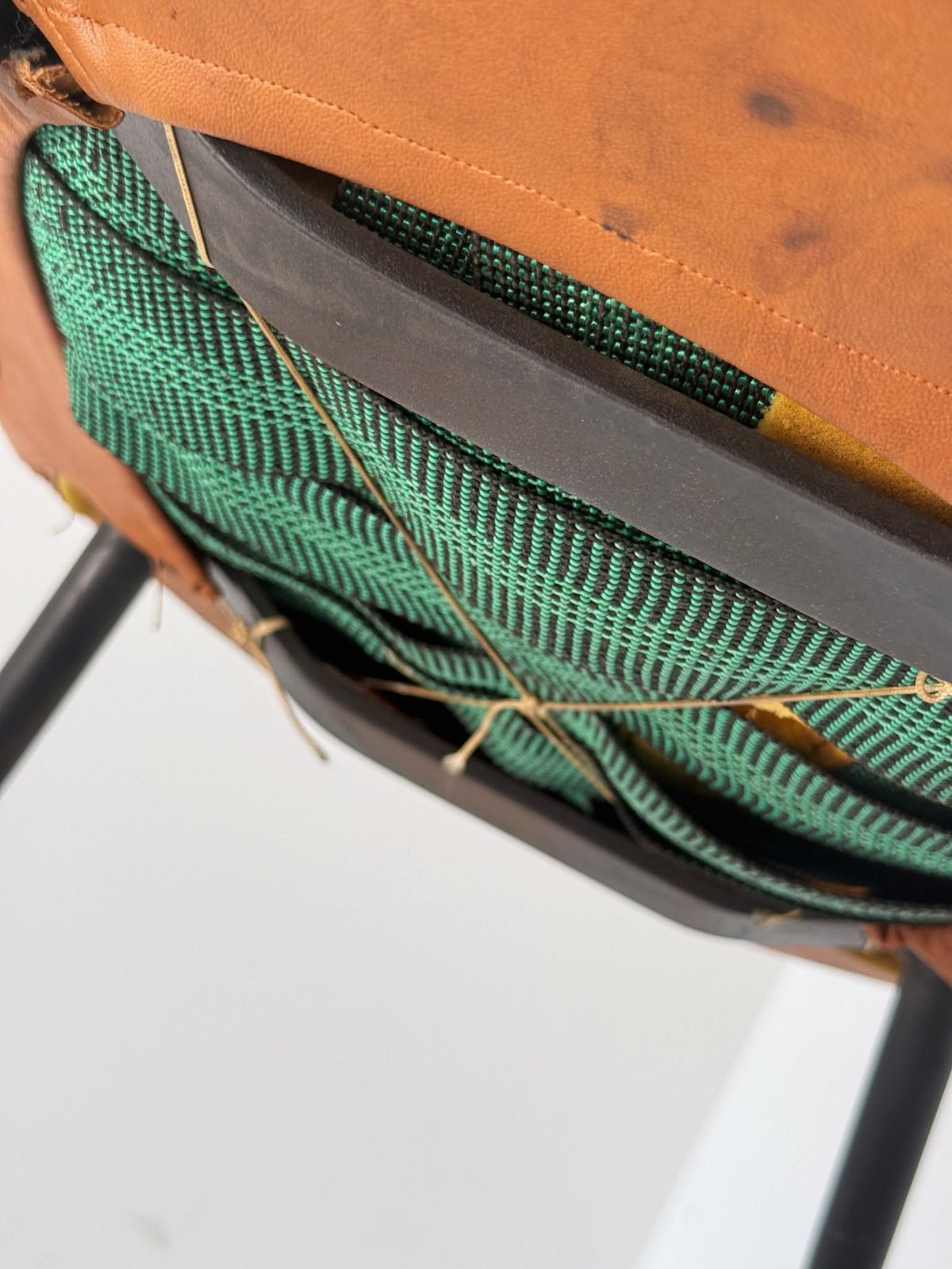 Poltroncina imbottita in pelle color cognac con struttura in metallo nero, anni ’50/’60.
