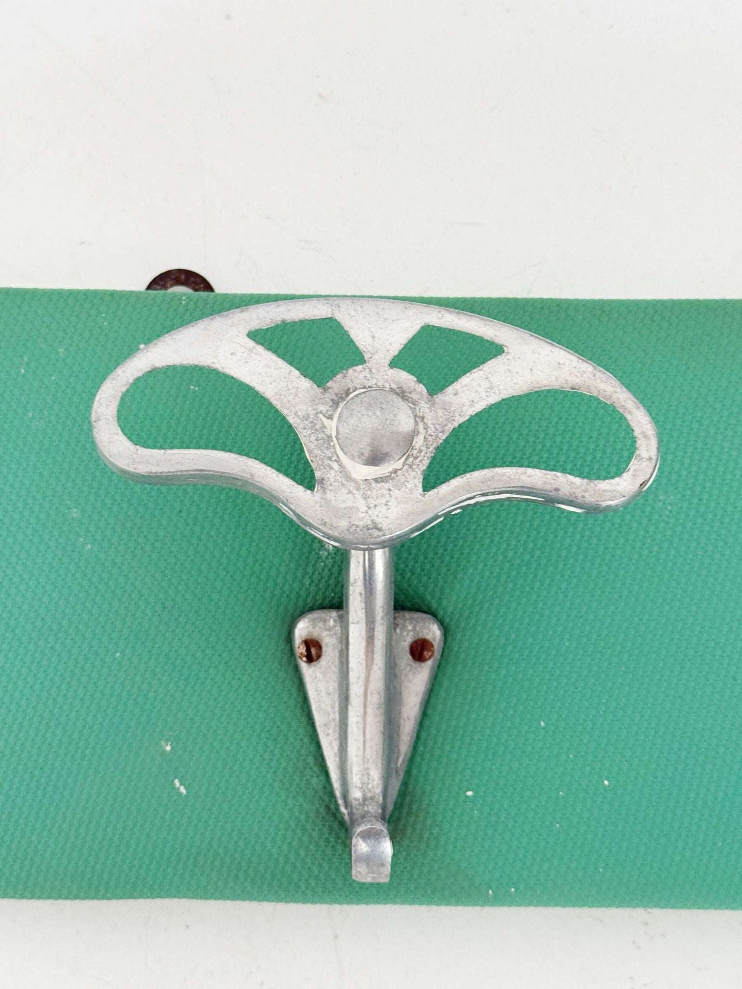 Metal wall coat hanger on green panel