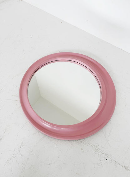 Round pink mirror on a white surface