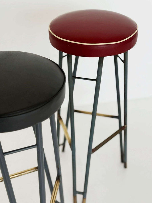 A pair of high stools with a painted metal frame, characterized by a sleek