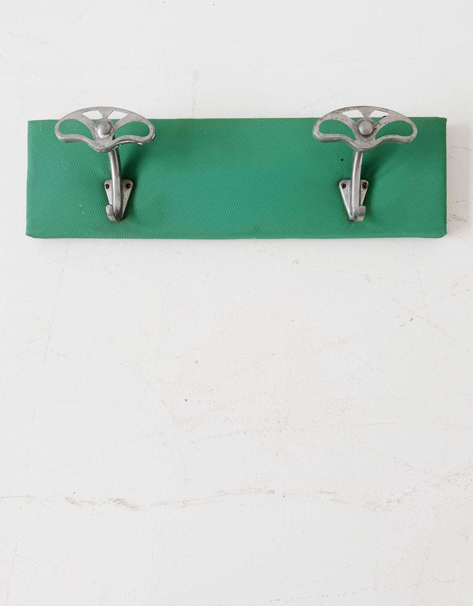 Metal wall coat hanger on green panel