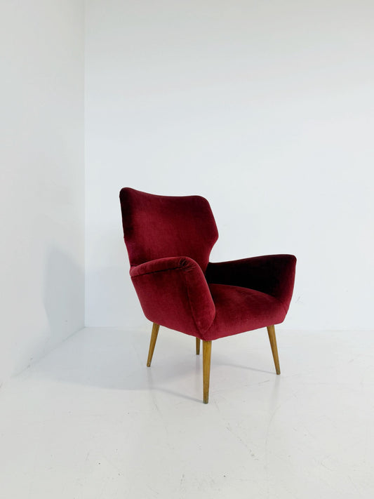 An elegant 1950s-style armchair upholstered in burgundy velve