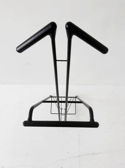 Appendiabiti da terra pieghevole in tubolare metallico verniciato nero, con struttura a montanti incrociati.
