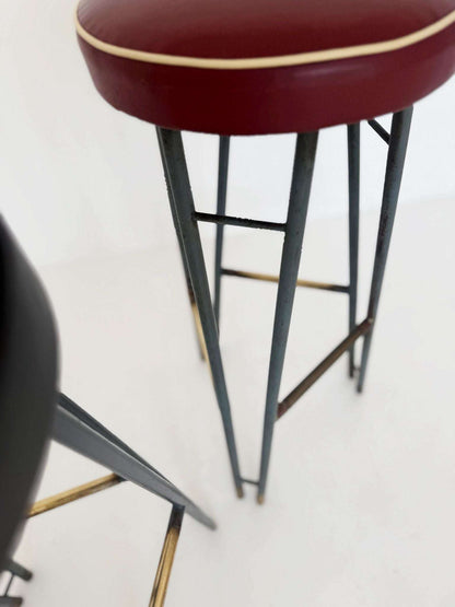 A pair of high stools with a painted metal frame, characterized by a sleek