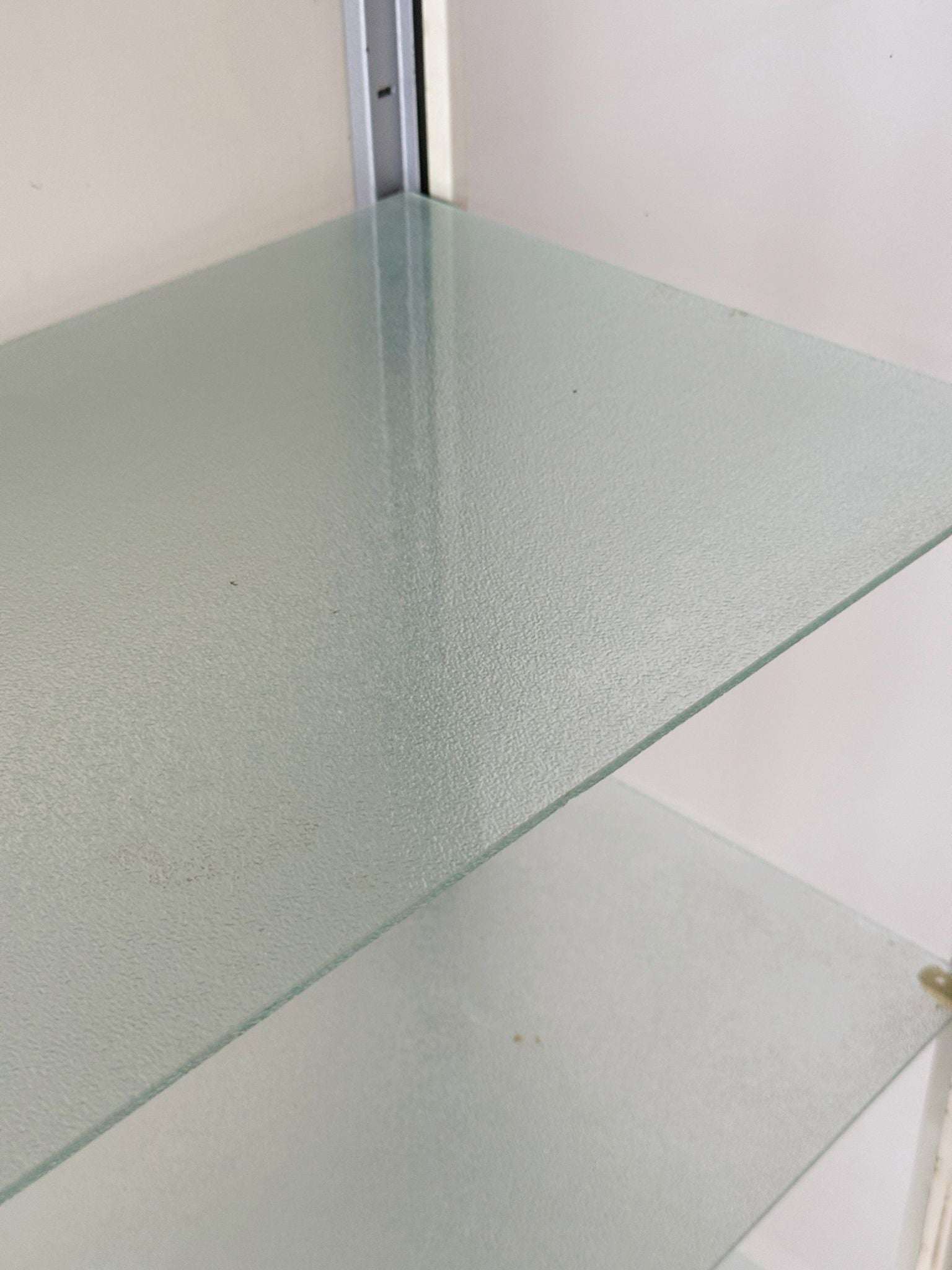 This ivory-colored lacquered metal display cabinet features a simple, functional design