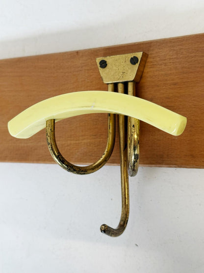 Wooden wall-mounted coat rack with three curved brass hooks and colored Bakelite
