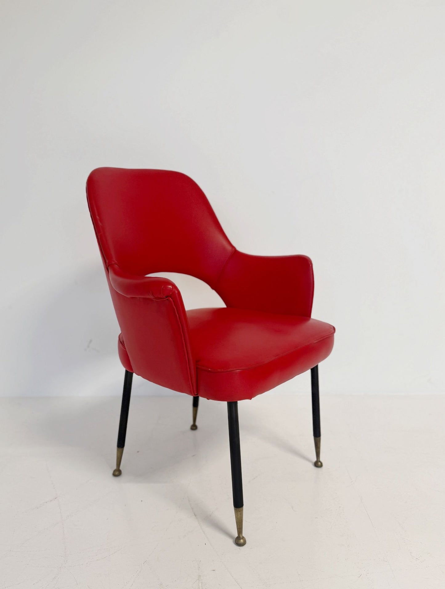 Poltrona italiana anni ’50 in skai rosso, con schienale sagomato e apertura posteriore.