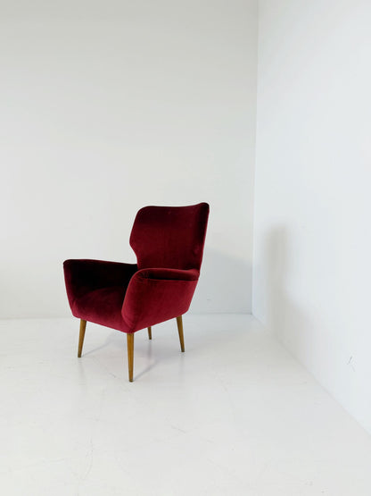 An elegant 1950s-style armchair upholstered in burgundy velve
