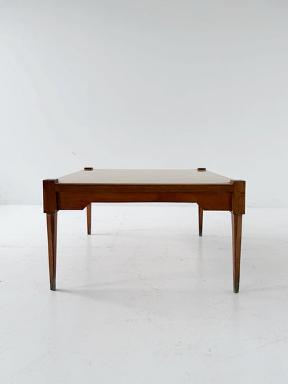 This mid-century coffee table features a solid wood frame and tapered
