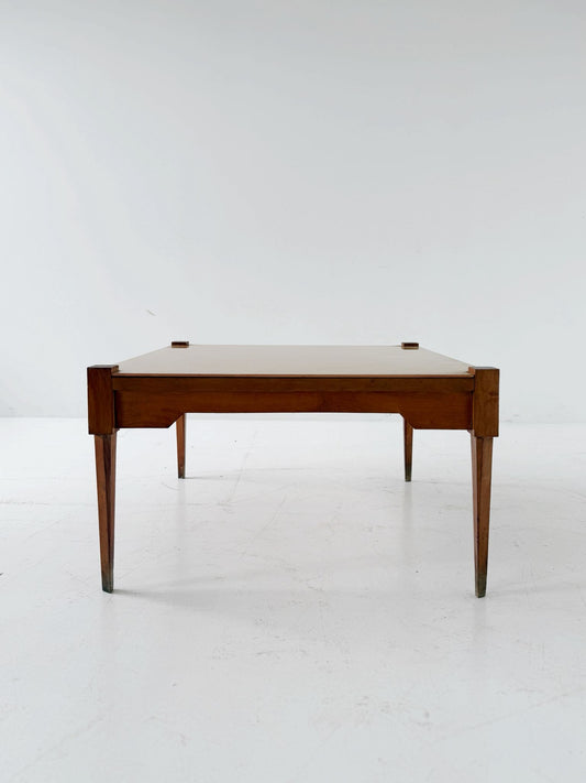 This mid-century coffee table features a solid wood frame and tapered