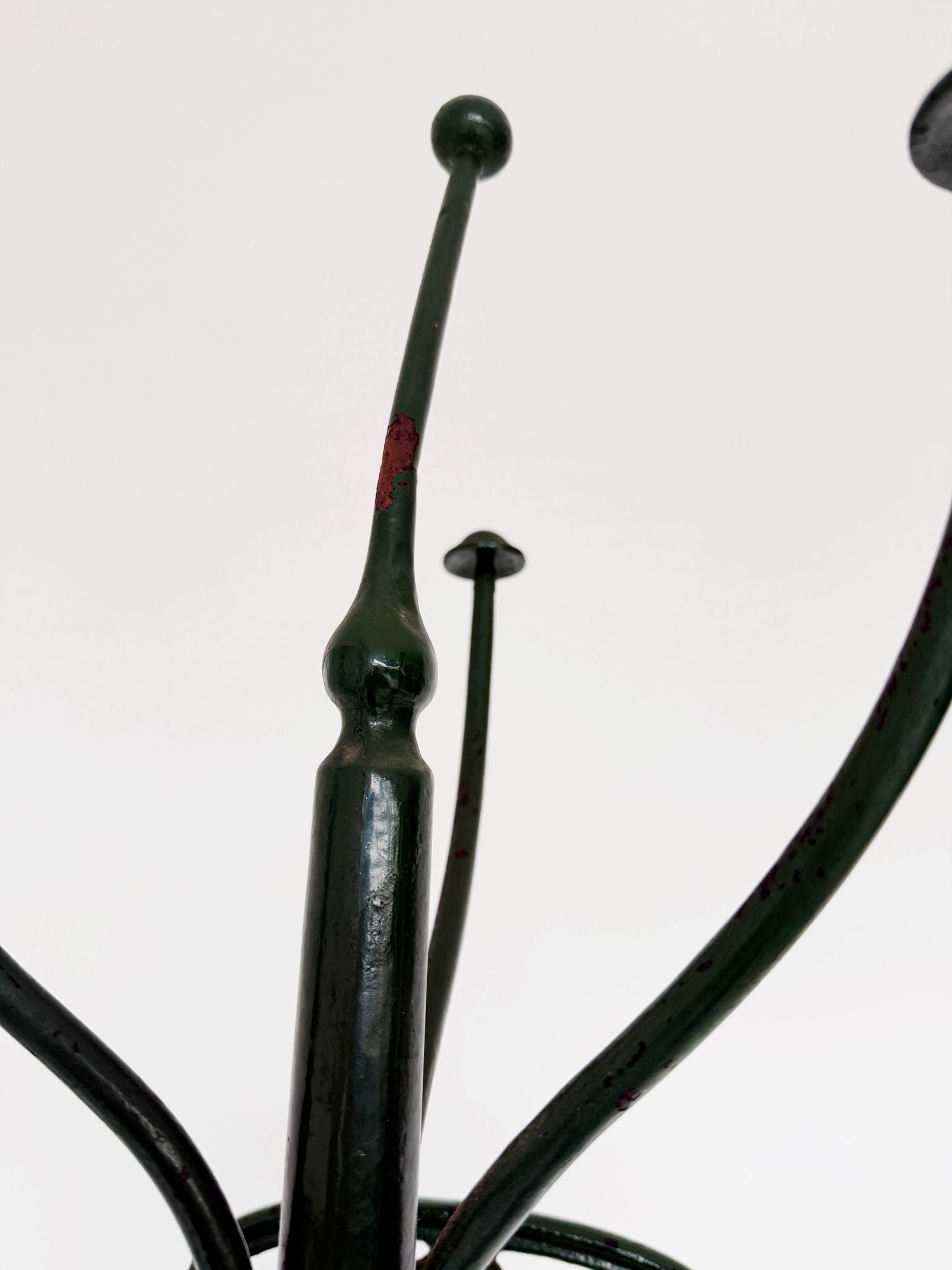 Floor coat rack made of dark green painted iron.