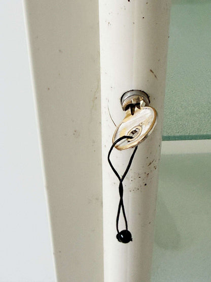 This ivory-colored lacquered metal display cabinet features a simple, functional design