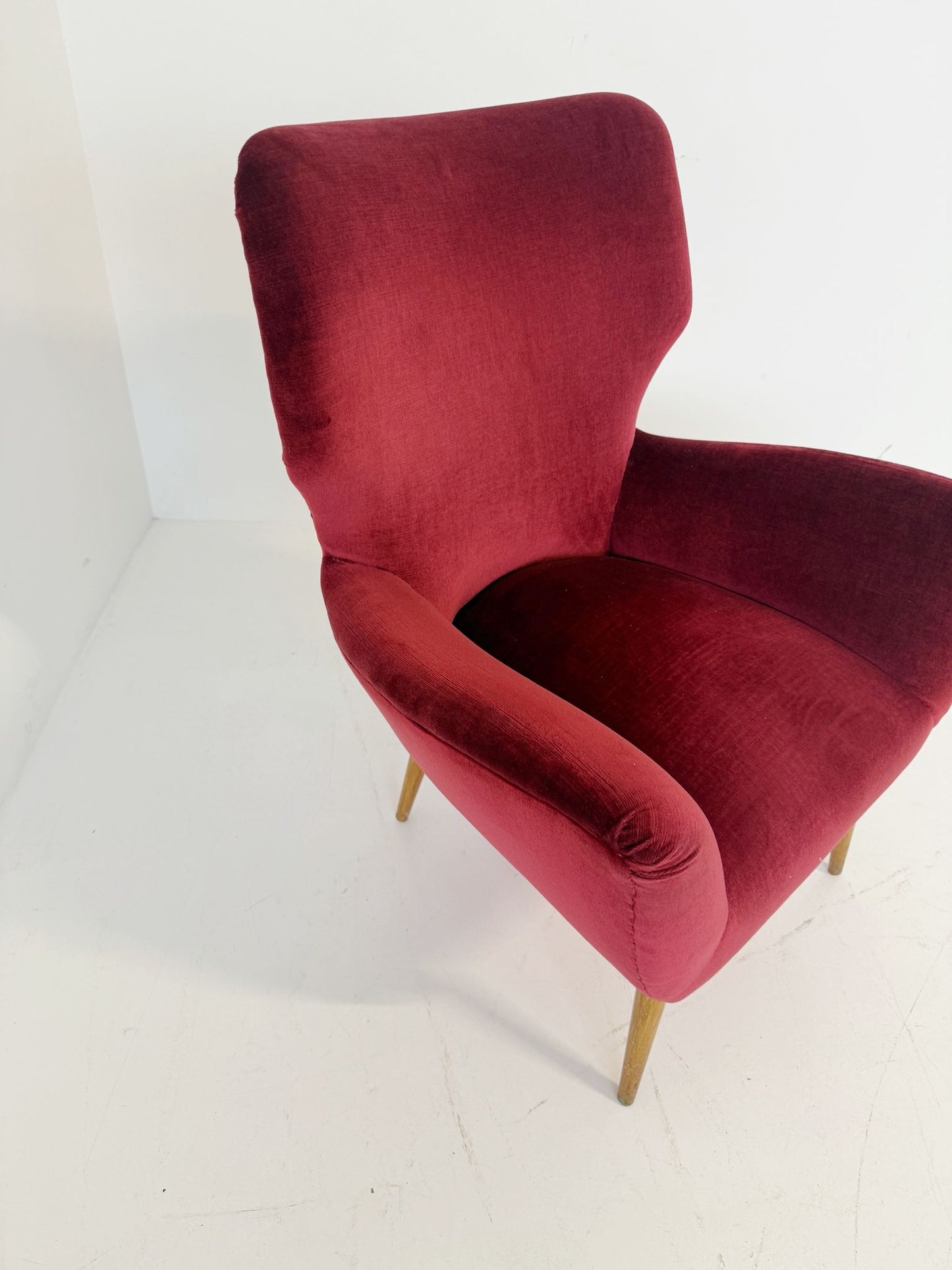 An elegant 1950s-style armchair upholstered in burgundy velve