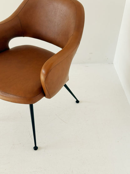 Poltroncina imbottita in pelle color cognac con struttura in metallo nero, anni ’50/’60.