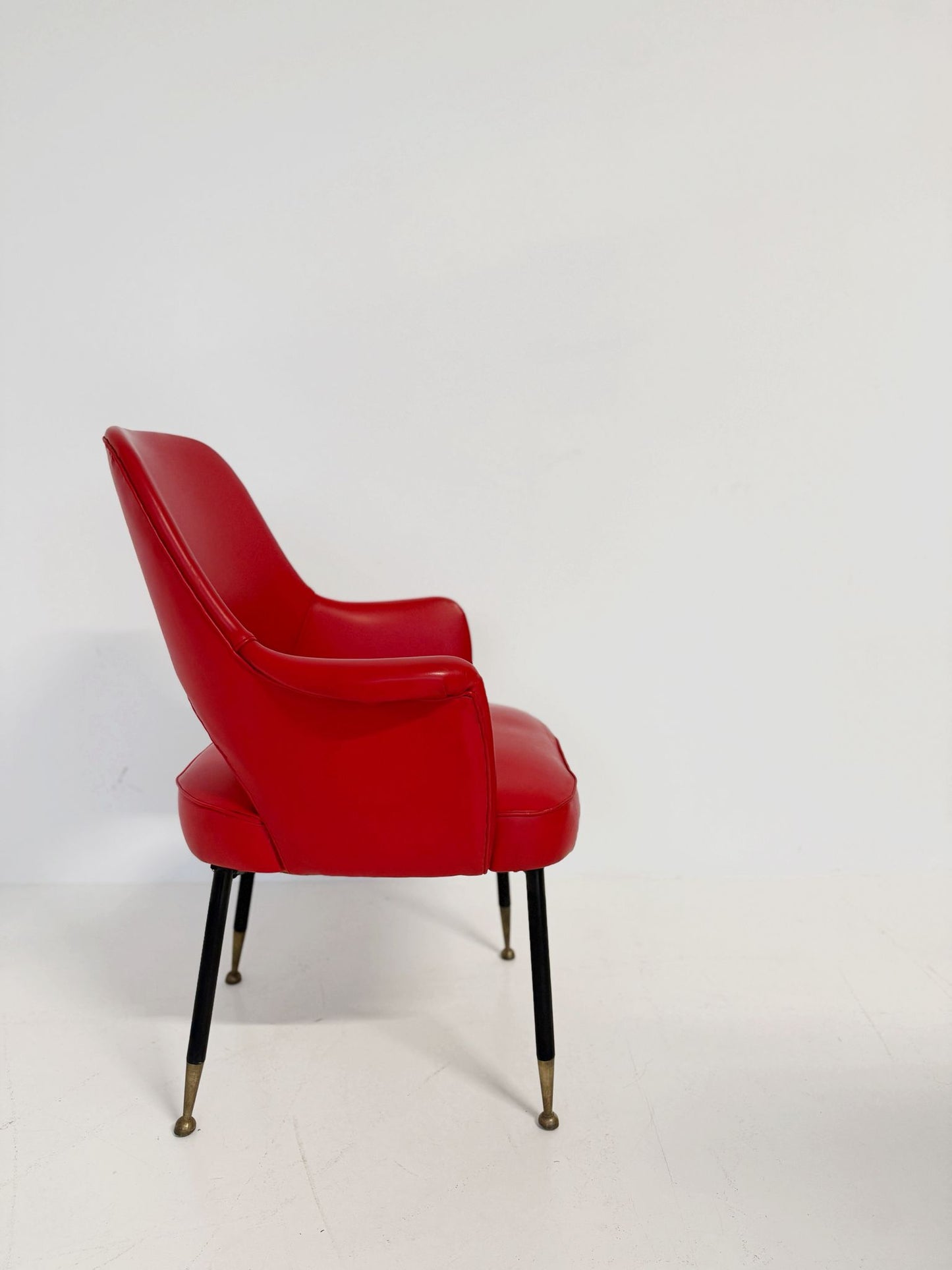 Poltrona italiana anni ’50 in skai rosso, con schienale sagomato e apertura posteriore.