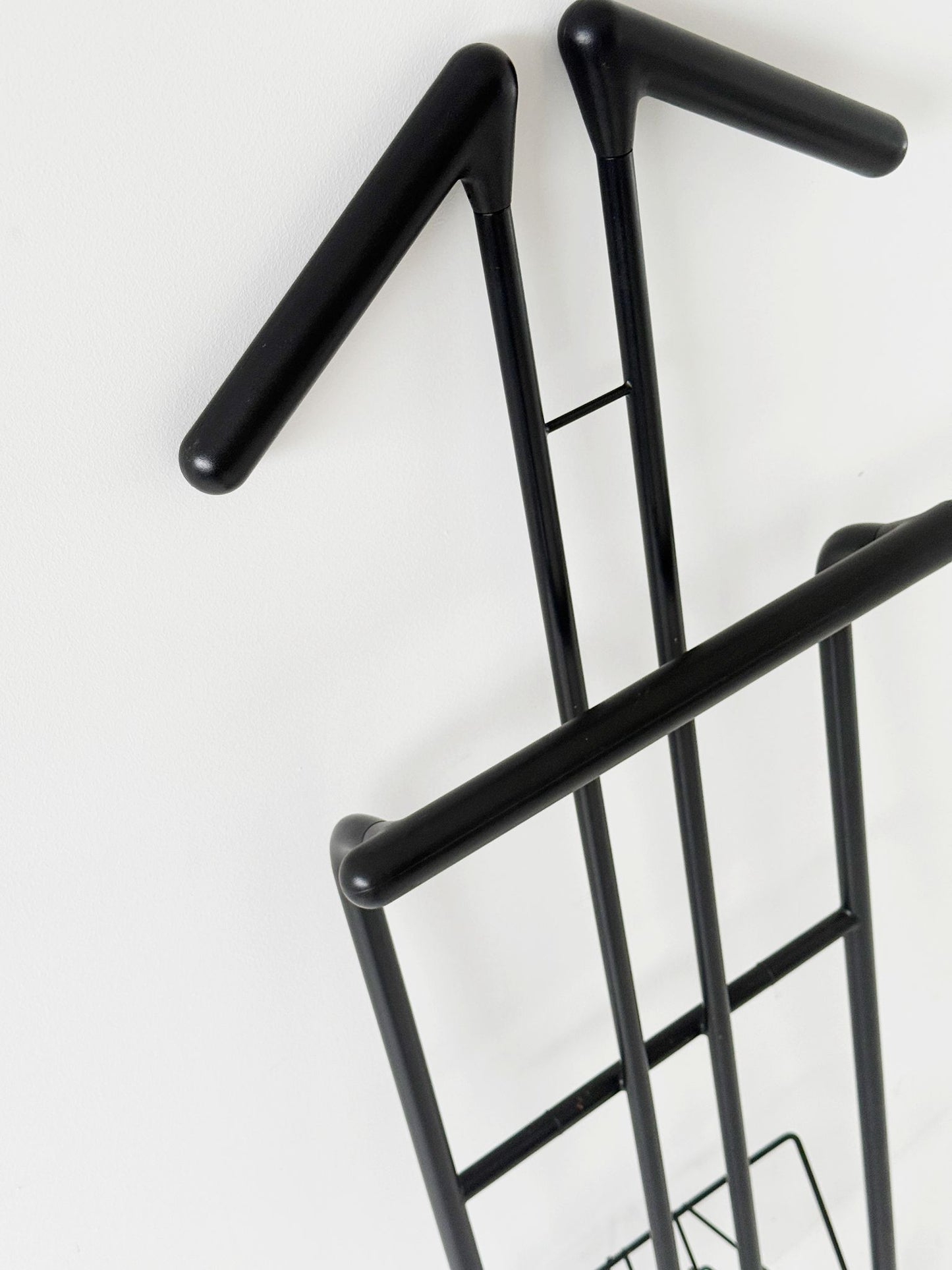 Appendiabiti da terra pieghevole in tubolare metallico verniciato nero, con struttura a montanti incrociati.
