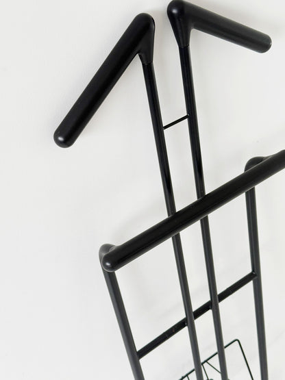 Appendiabiti da terra pieghevole in tubolare metallico verniciato nero, con struttura a montanti incrociati.
