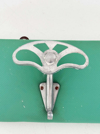 Metal wall coat hanger on green panel