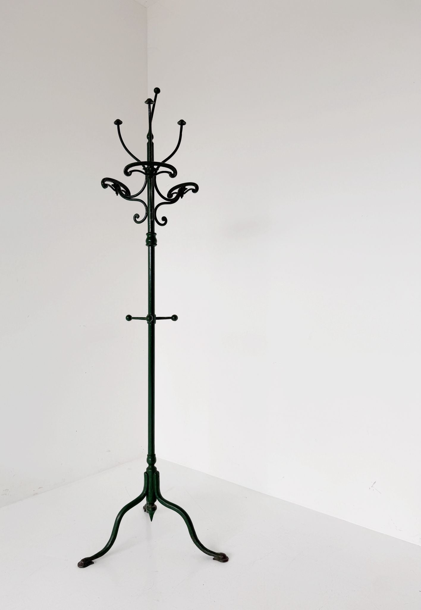 Floor coat rack made of dark green painted iron.