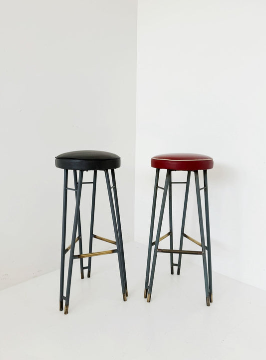 Una coppia di sgabelli alti con struttura in metallo verniciato, caratterizzati da un design elegante
