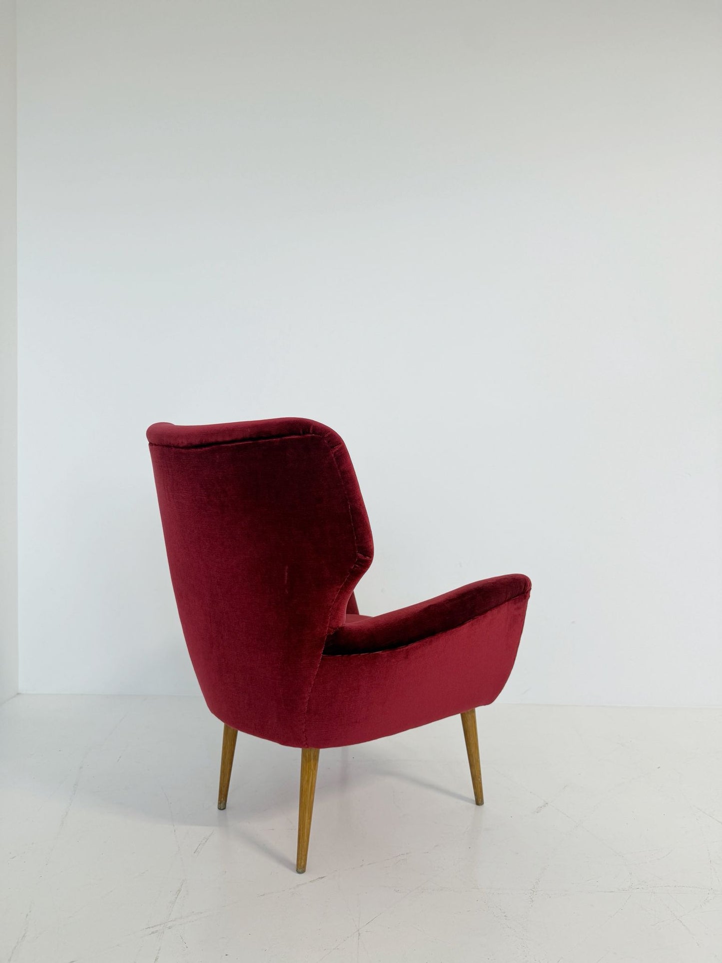 An elegant 1950s-style armchair upholstered in burgundy velve