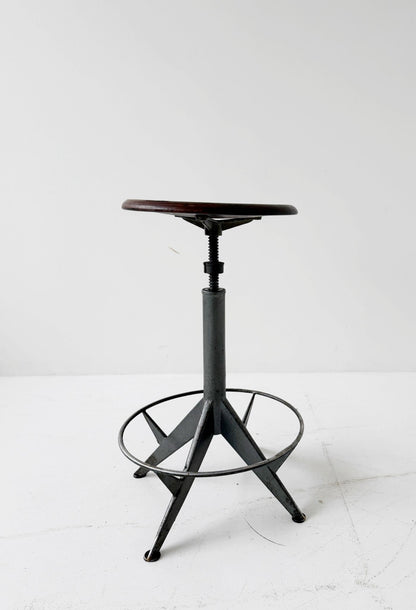 An adjustable industrial stool with a distinctly workshop/laboratory feel, boasting a strong, authentic presence.