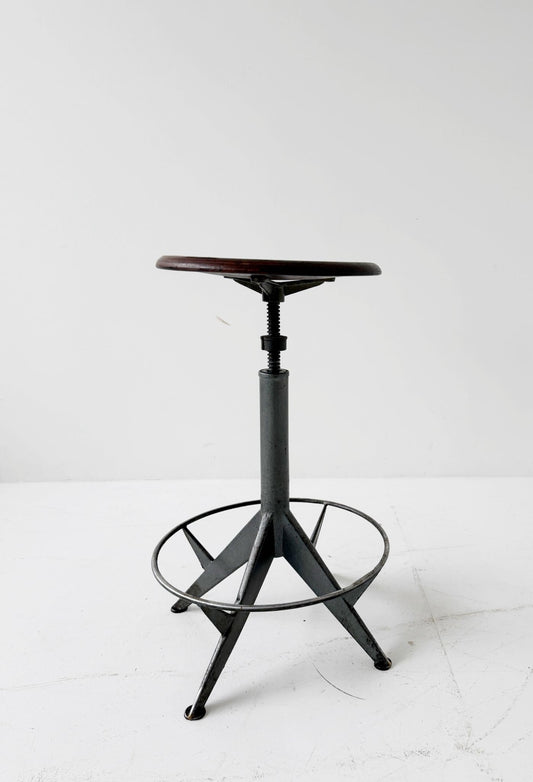 An adjustable industrial stool with a distinctly workshop/laboratory feel, boasting a strong, authentic presence.