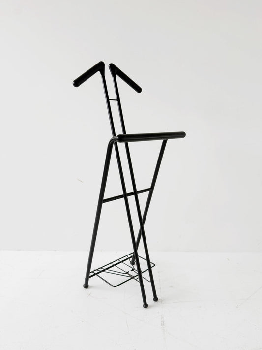 Appendiabiti da terra pieghevole in tubolare metallico verniciato nero, con struttura a montanti incrociati.
