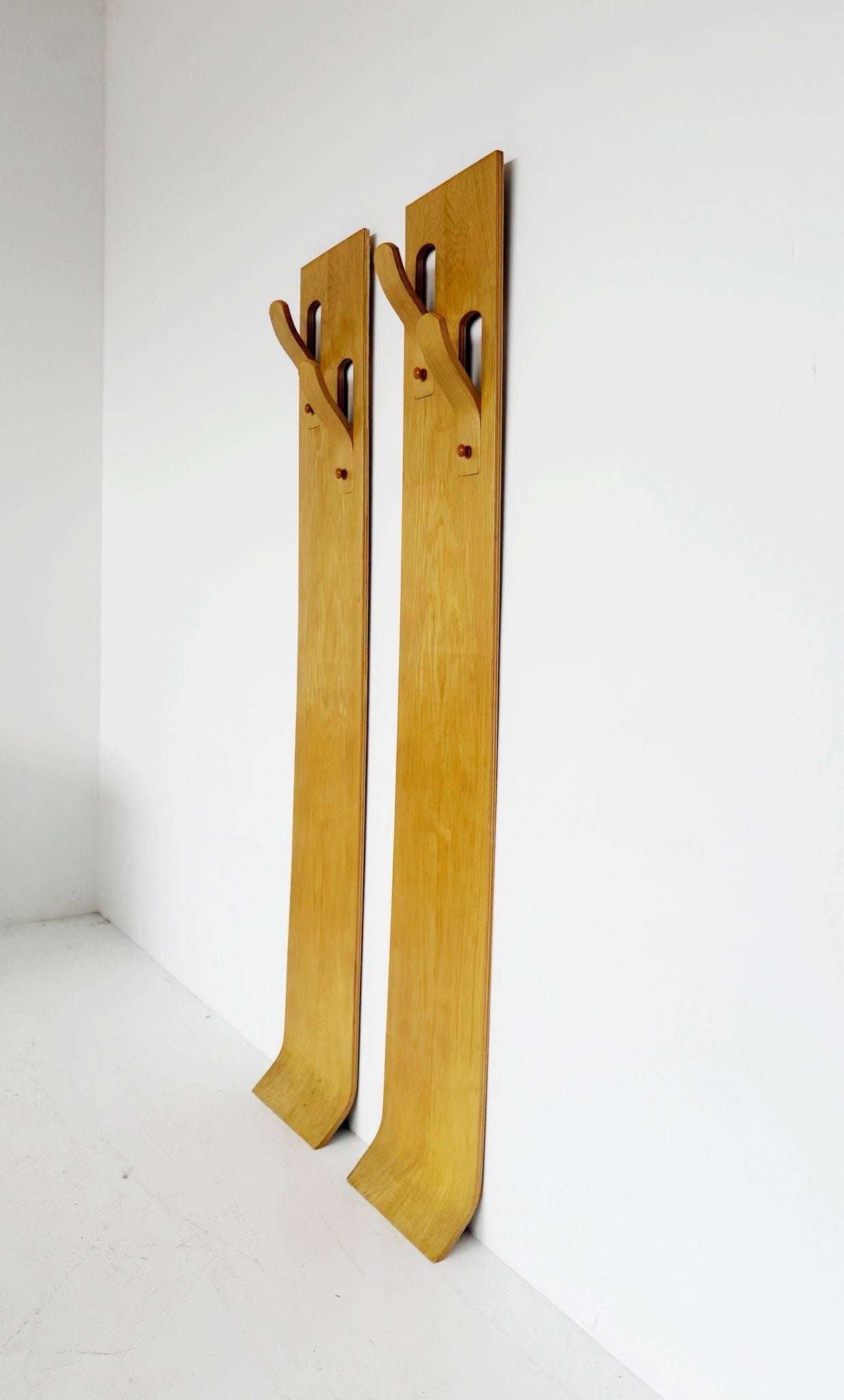 A pair of wall-mounted coat racks composed of two independent vertical modules,